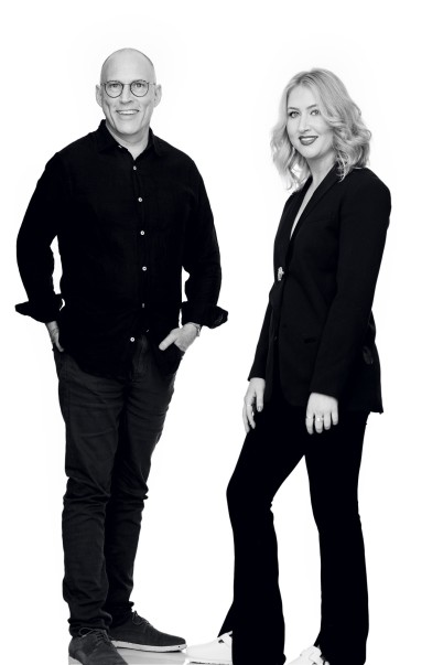 A black and white photo of Erin and Duncan wearing black clothing against a white backdrop.
