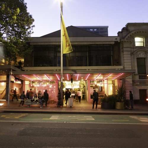 Image of Q Theatre exterior with bustling people and traffic