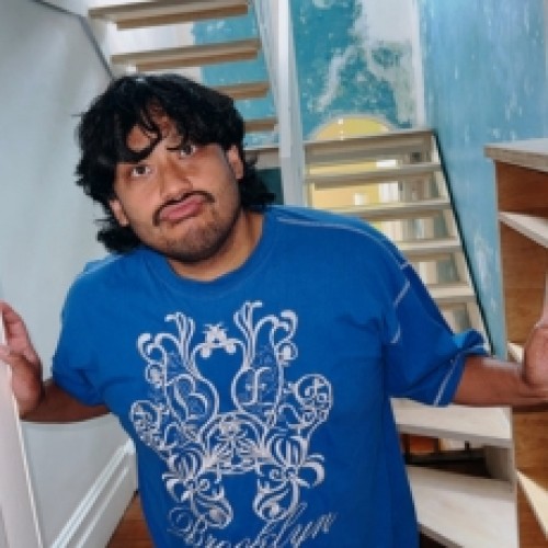  Comedian David Correos pouting his lips, wearing a blue tshirt and standing in a blue stairwell