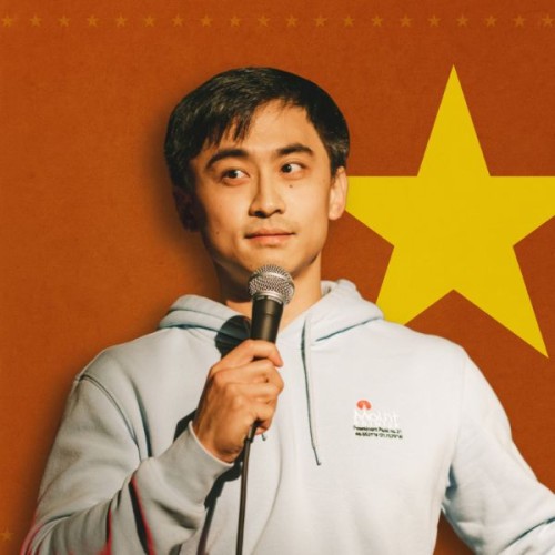 A picture of henry holding a microphone in a grey hoodie agaisnt a brown background with a yellow star. 