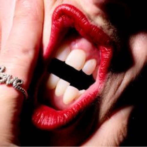 An image of an open mouth gripped between fingers