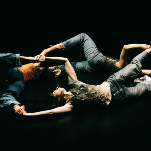 Three people lying in a circle, their limbs sprawled forming abstract shapes